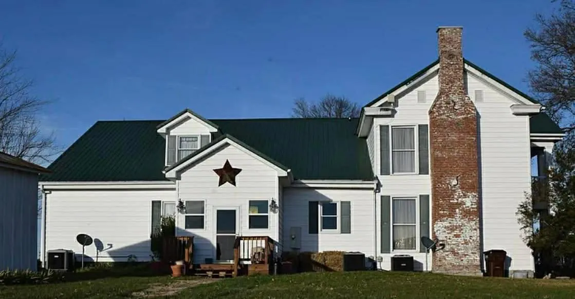 Frenzy Outdoors farmhouse hunting lodge with a green roof in the Kentucky countryside