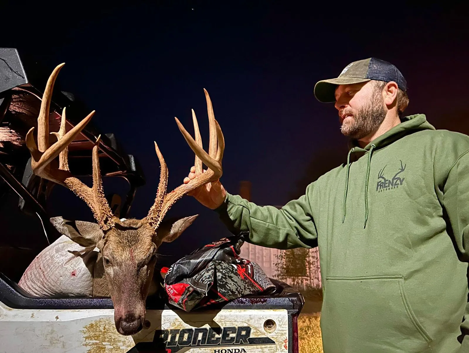 Hunter posing with a tall-tined buck at sunset